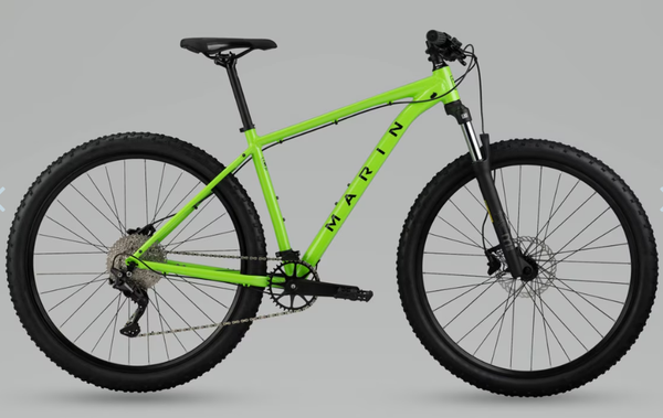 Green trail bicycle with knobby tires, disc brakes, and front suspension fork